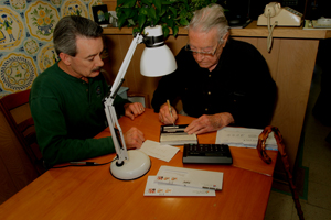 Man signs check with signature guide with help of family member