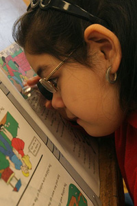 girl using a magnifier to read her schoolwork