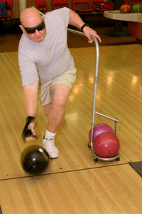 man with dark glasses using a guide rail to bowl
